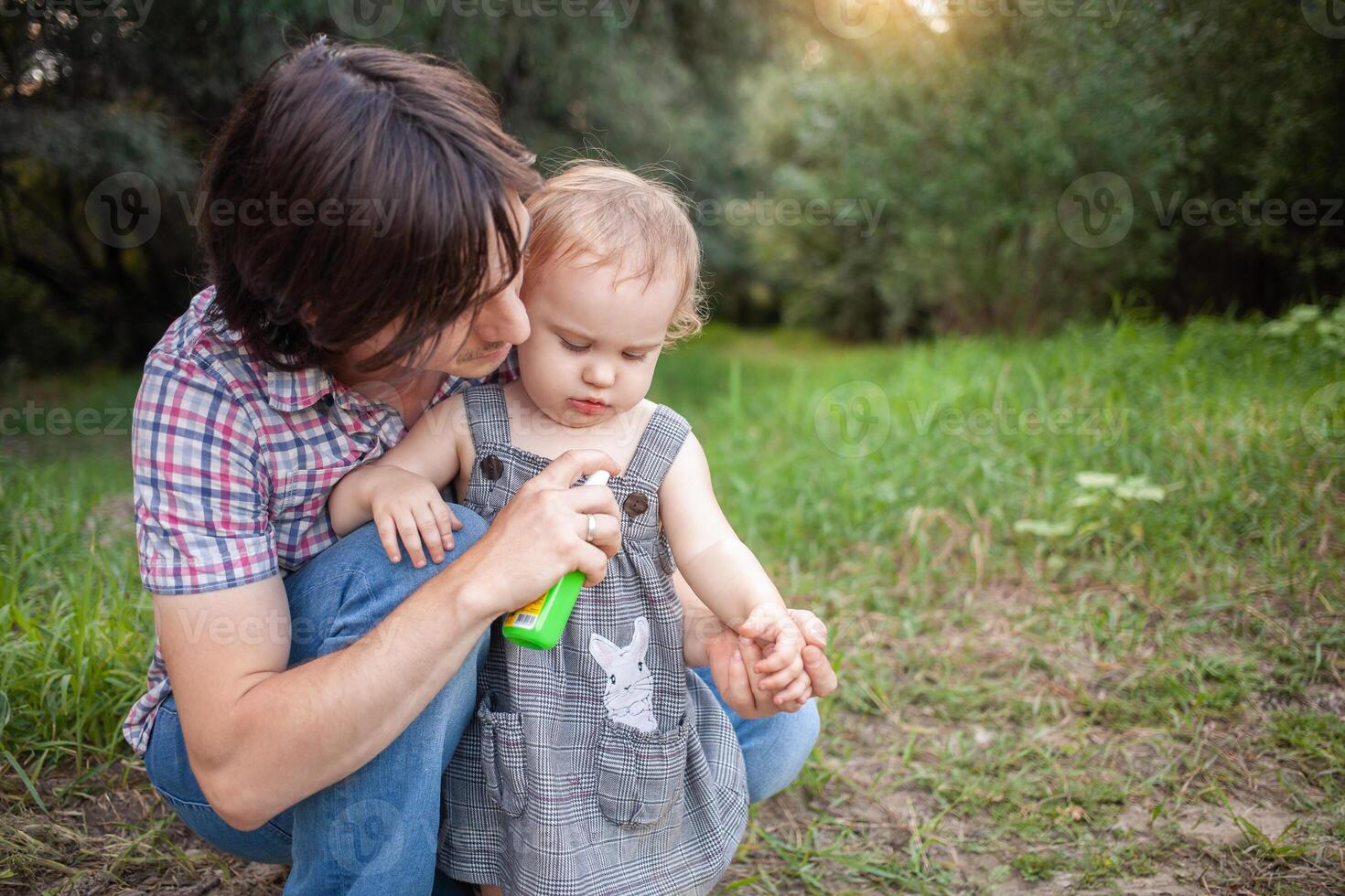 Papai guloseimas dele filha com mosquito spray. a homem usa spray em a criança braços e pernas. proteção a partir de mosquitos dentro a floresta. spray a partir de mosquitos dentro natureza foto