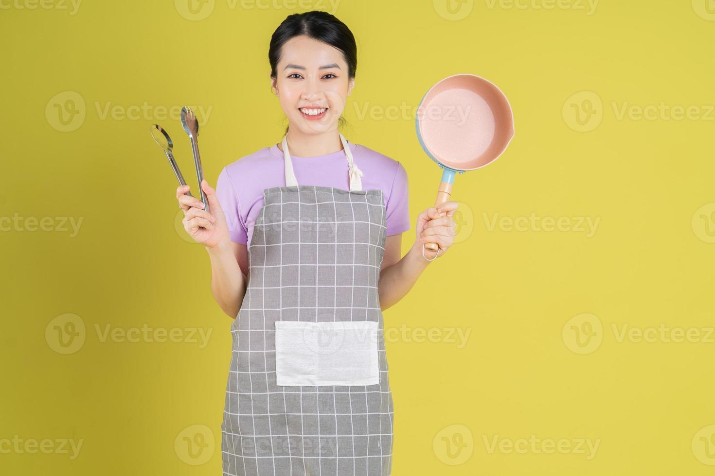 jovem dona de casa asiática posando em fundo amarelo foto