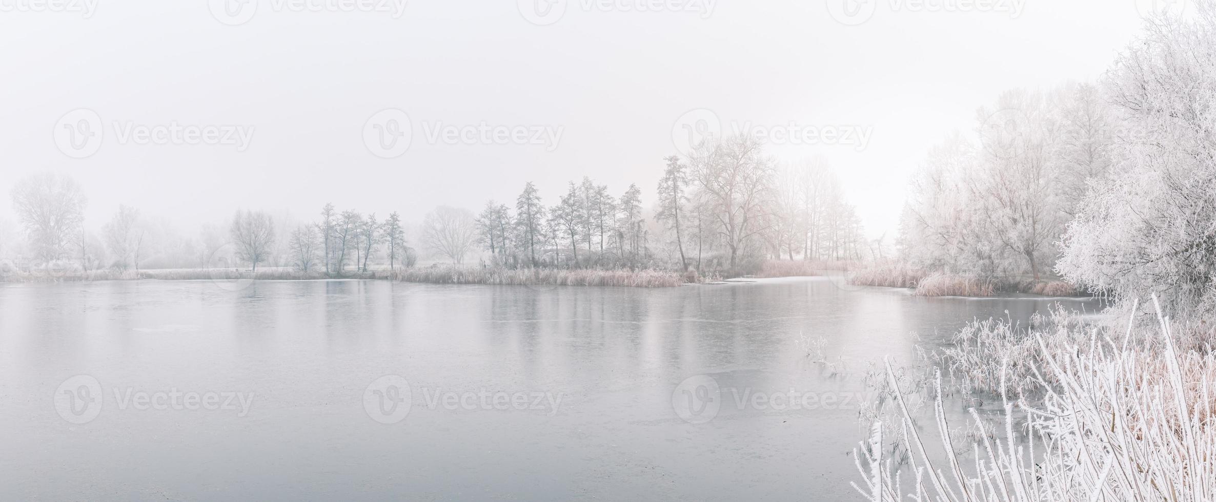 floresta de inverno no rio ao pôr do sol. paisagem panorâmica com árvores nevadas, sol, lindo rio congelado com reflexo na água. sazonal. árvores de inverno, lago e céu azul. rio gelado de neve. clima foto