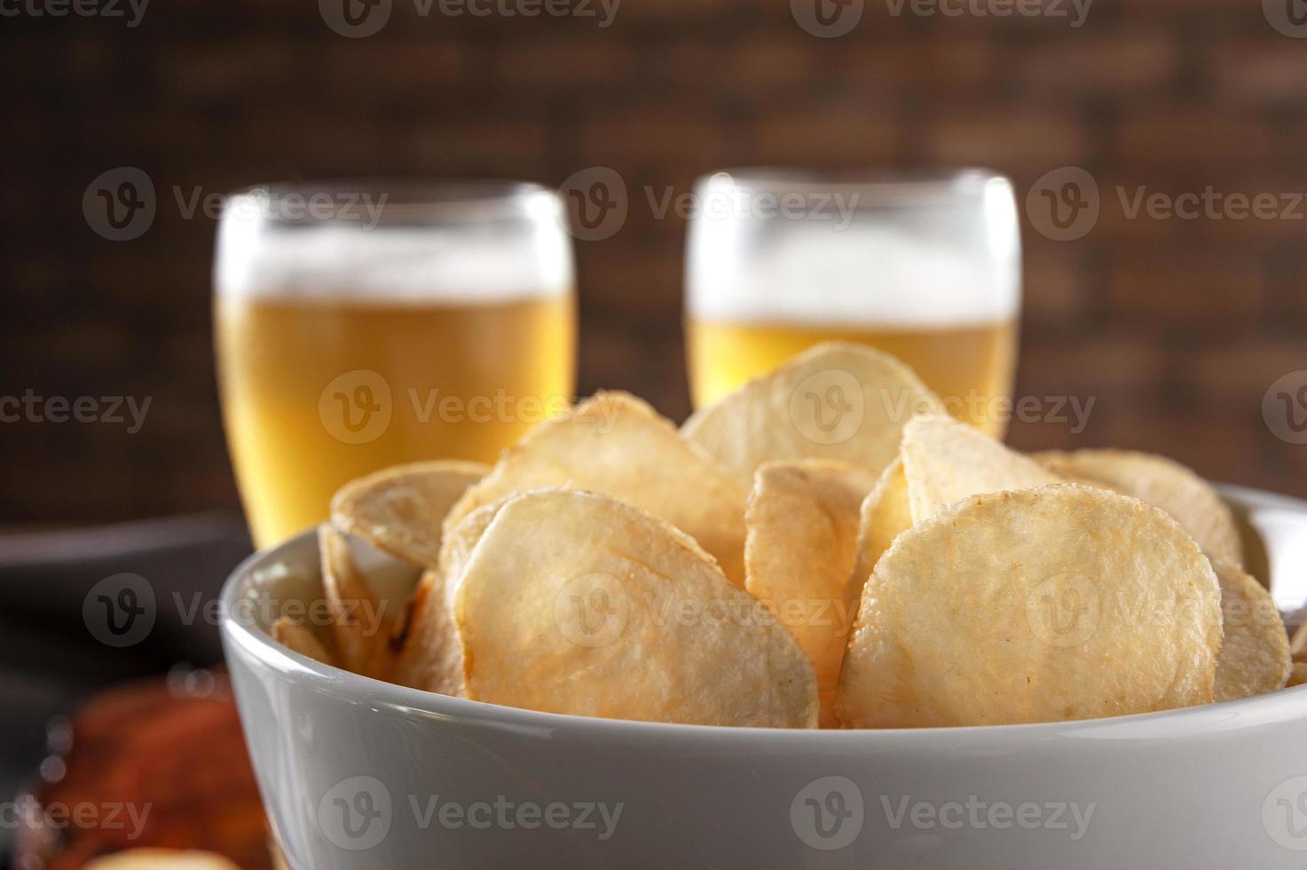 batata frita em uma tigela com dois copos de cerveja foto