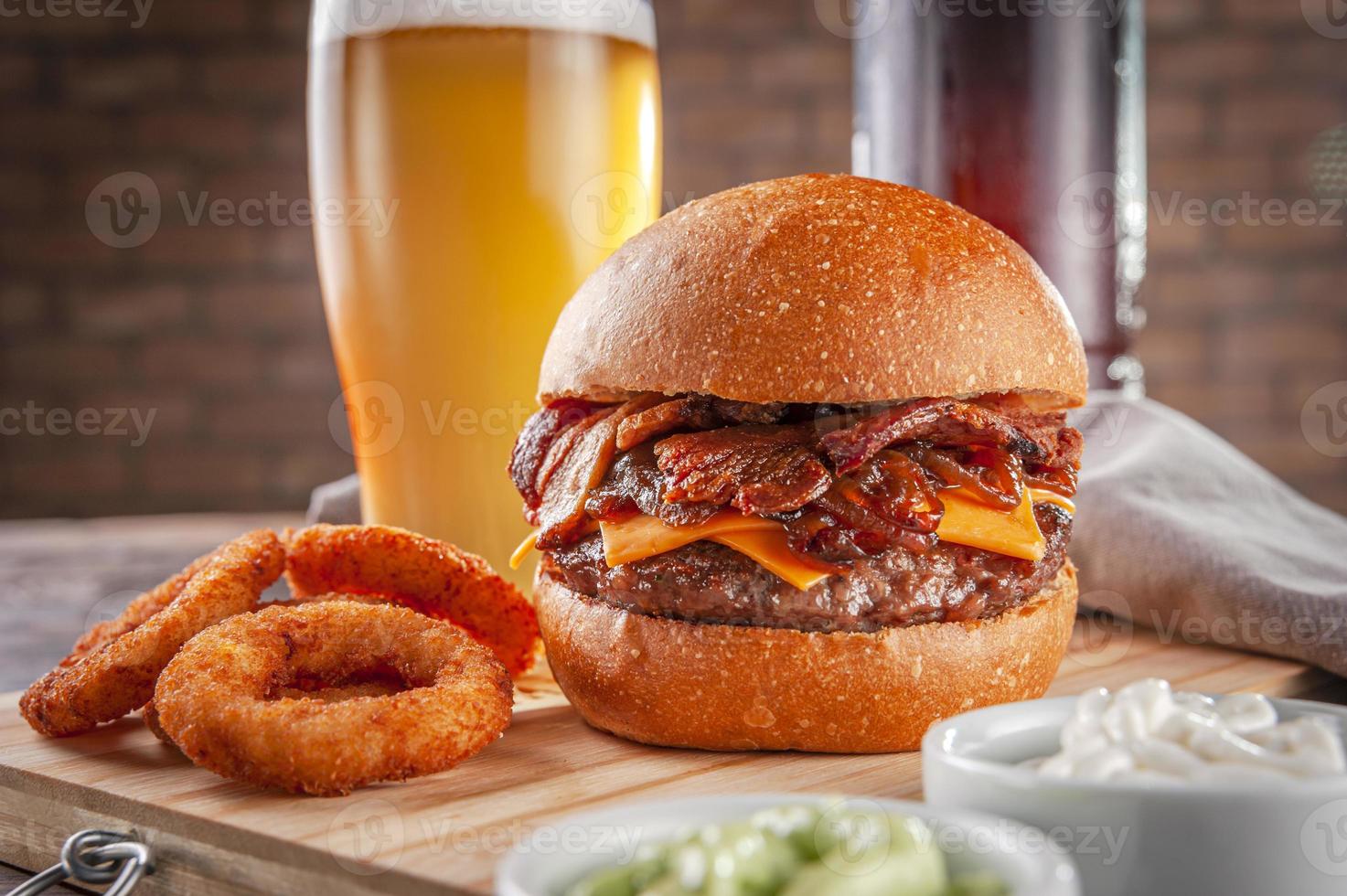 delicioso hambúrguer de bacon com rodelas de cebola e cerveja. foto