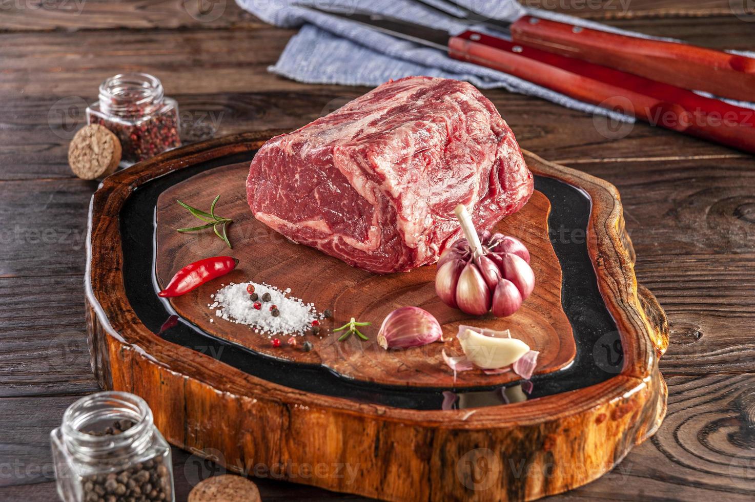 Entrecosto de carne crua em uma tábua de madeira com especiarias. foto