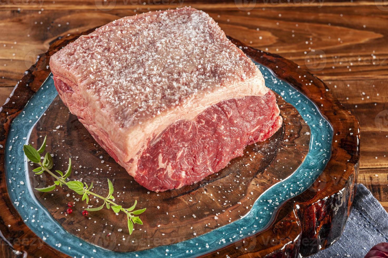 Bife de lombo cru - chouriço argentino em uma tábua de madeira resinada com sal parrilla e especiarias. foto