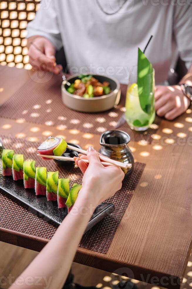 menina comendo Sushi rolos embrulhado com atum e abacate foto