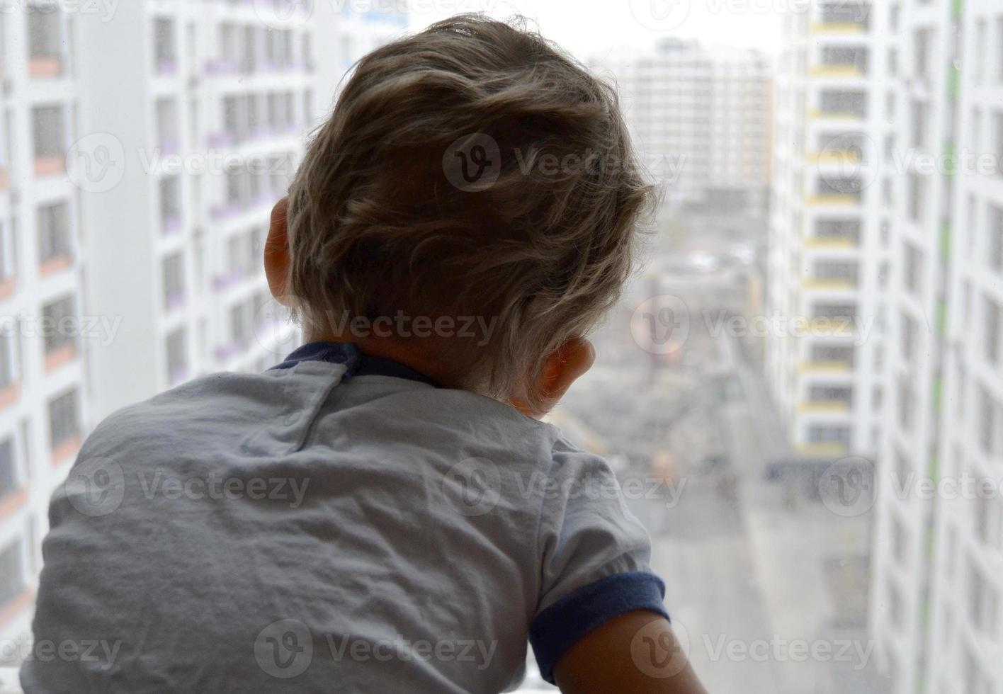 lindo menino com rosto de criança posando para fotógrafo perto da janela foto