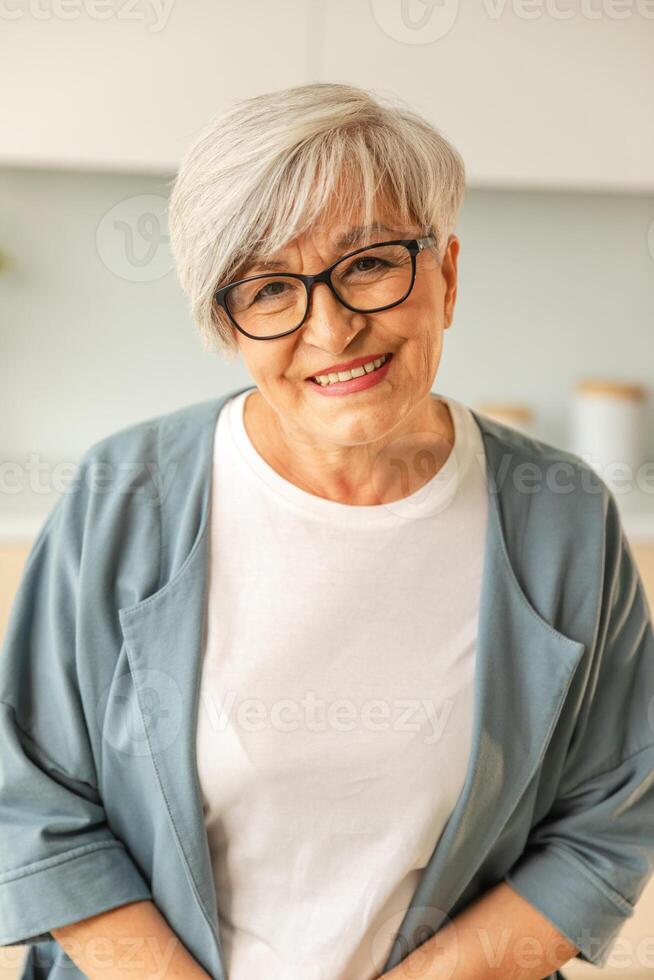 retrato do confiante à moda europeu meio envelhecido Senior mulher. Mais velho maduro anos 60 senhora sorridente às lar. feliz atraente Senior fêmea olhando Câmera fechar acima face Tiros na Cabeça retrato. feliz pessoas foto