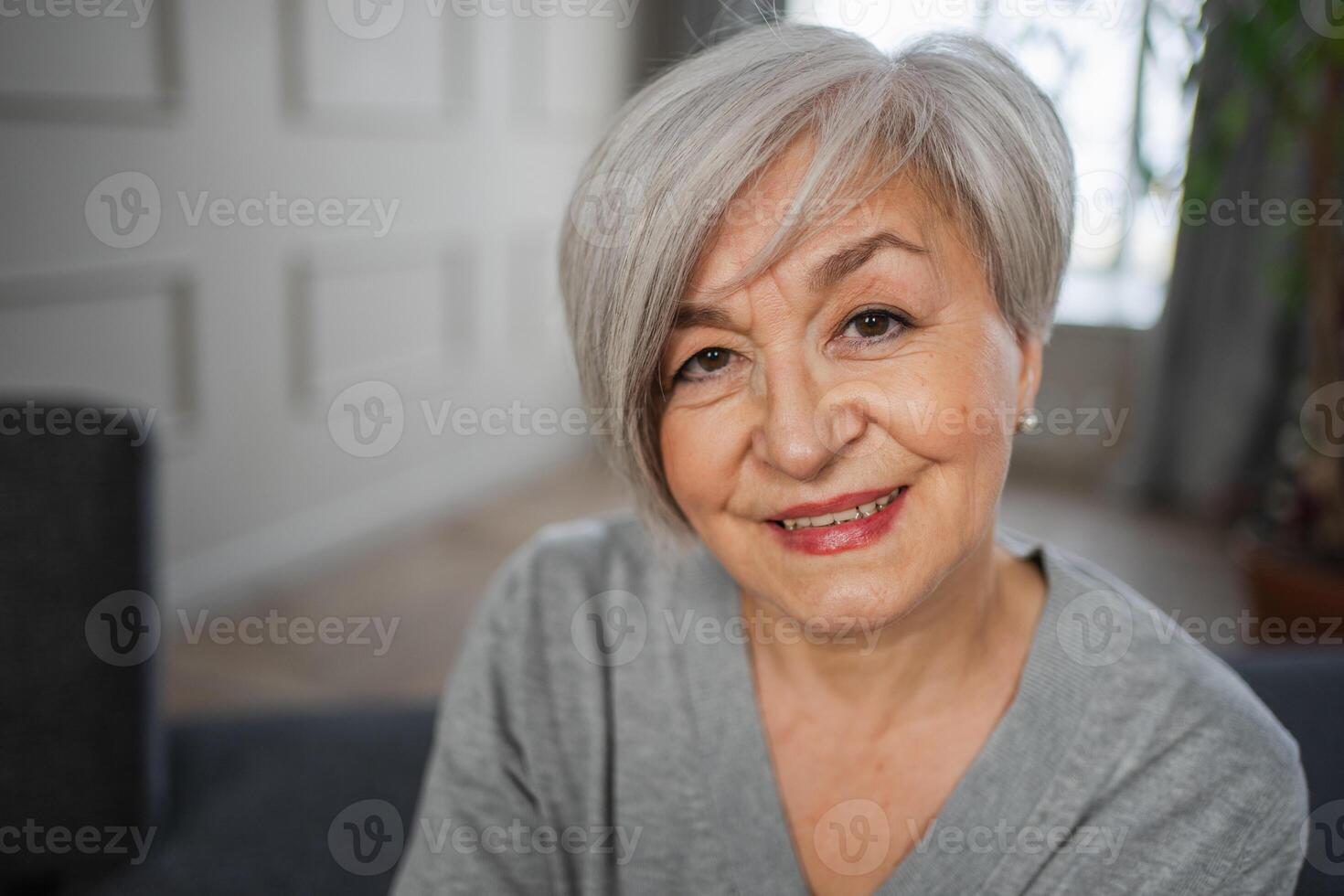 retrato do confiante à moda europeu meio envelhecido Senior mulher. Mais velho maduro anos 60 senhora sorridente às lar. feliz atraente Senior fêmea olhando Câmera fechar acima face Tiros na Cabeça retrato. feliz pessoas foto