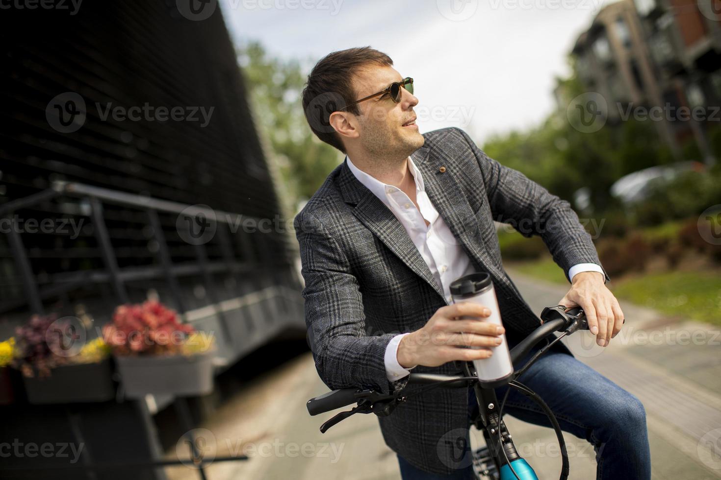 jovem empresário na ebike com uma xícara de café para viagem foto