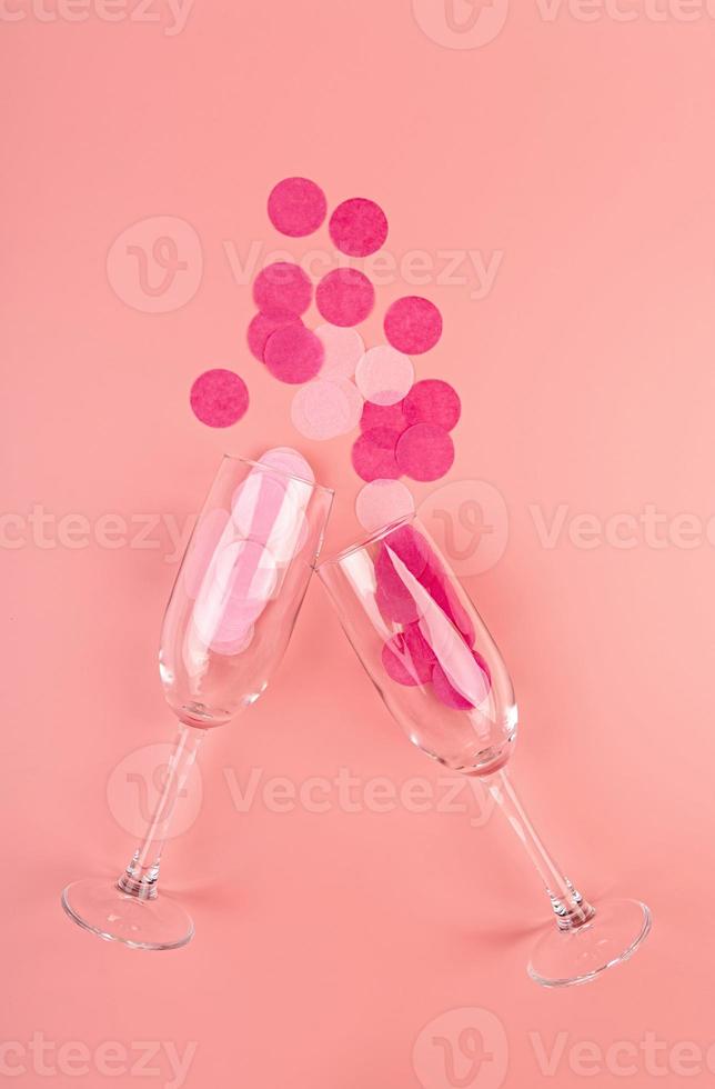 taças de champanhe em um fundo rosa com confete foto