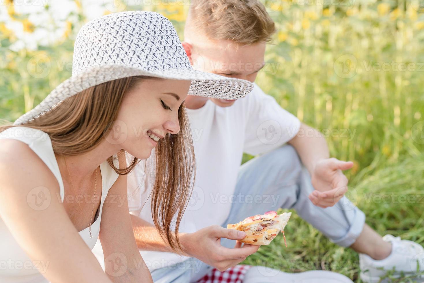 jovem casal fazendo piquenique no campo de girassol foto