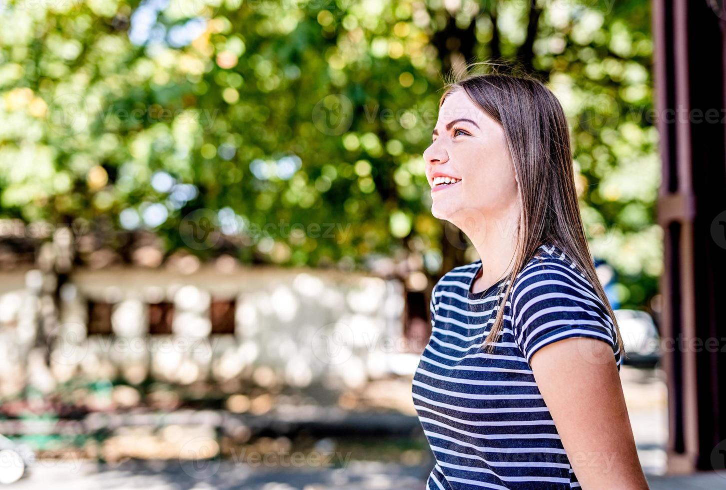 fechar o retrato de uma bela jovem caucasiana sorrindo e olhando ao ar livre em um dia ensolarado foto