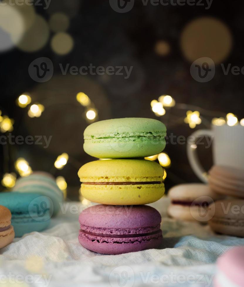 pilha de macaroons na mesa, luzes de fada e fundo de bokeh foto