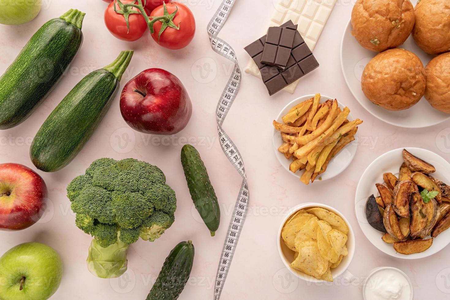 conceito de comida saudável e não saudável. frutas e vegetais vs doces e batatas fritas vista de cima plano foto