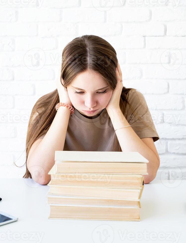 colegial deprimida com uma pilha de livros foto