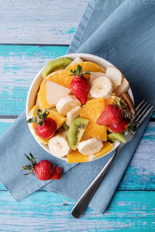 Salada de frutas frescas em fundo de madeira azul, vista superior, espaço de cópia foto