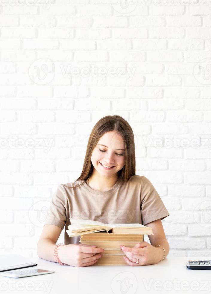 adolescente sorridente e feliz segurando uma pilha de livros foto