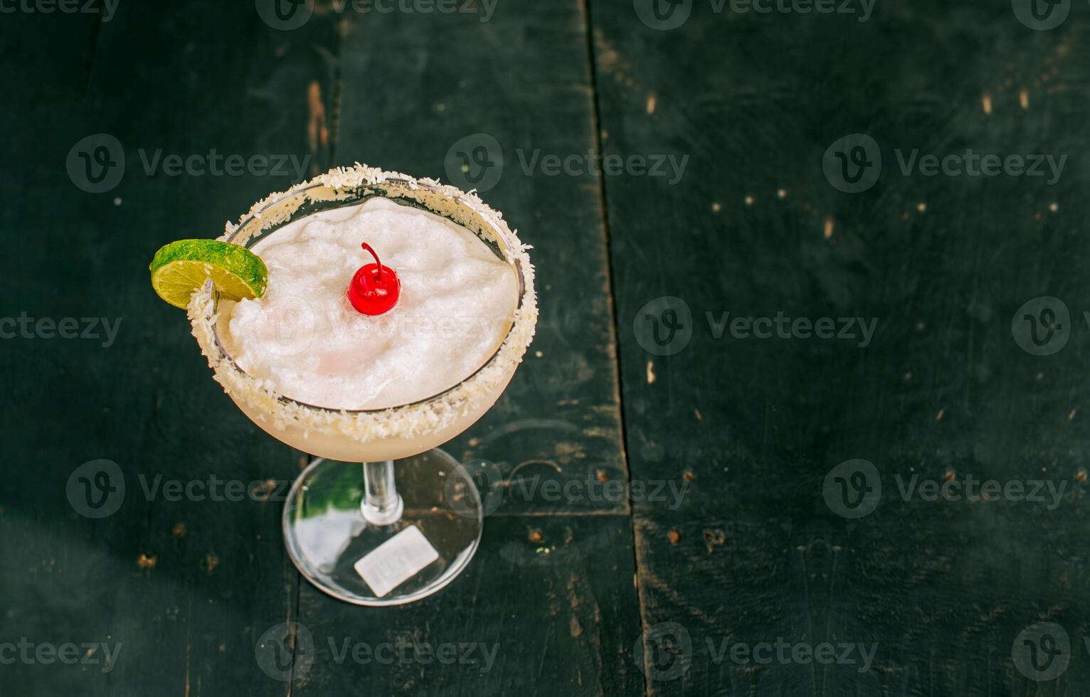 coco Margarita com cereja em de madeira mesa. congeladas coco coquetel com cereja em topo em de madeira mesa foto