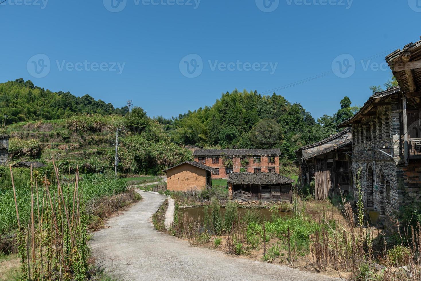 uma estrada que leva a uma longa distância no campo, com casas e florestas verdes ou campos foto