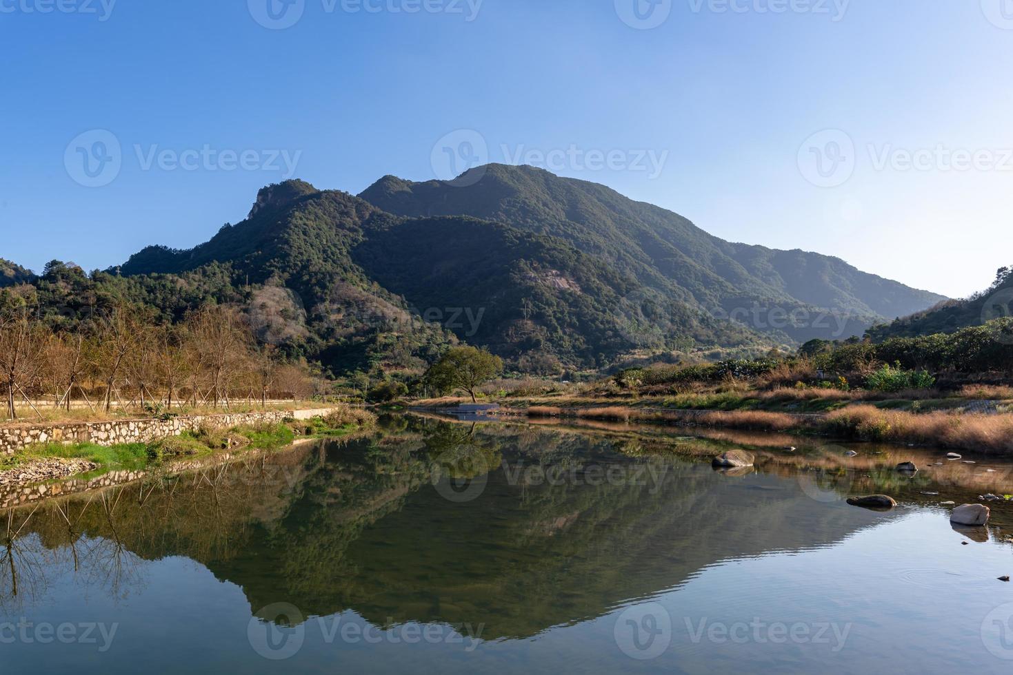 o rio do país reflete a montanha, e as aldeias e florestas estão sob o céu azul foto