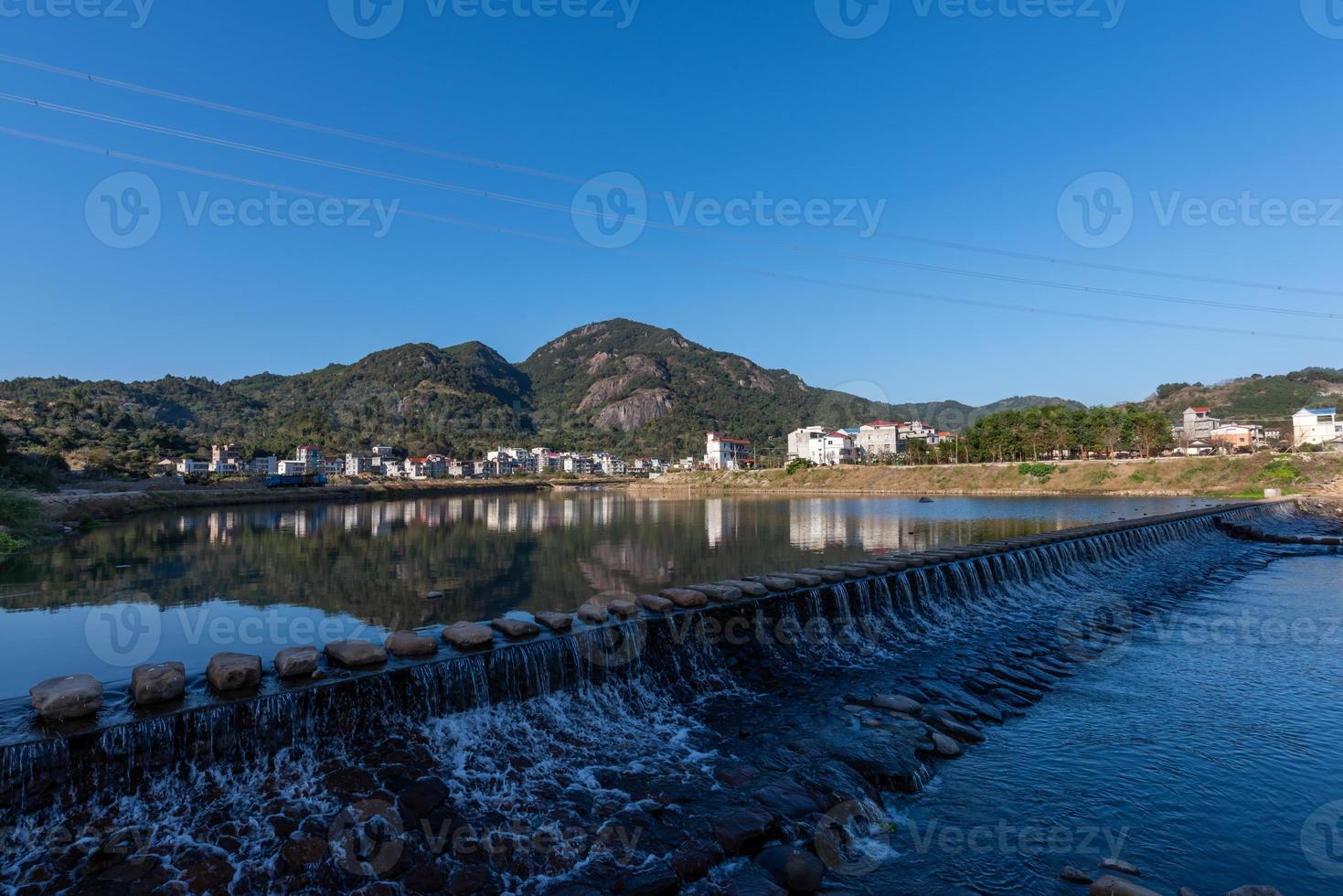 o rio do país reflete a montanha, e as aldeias e florestas estão sob o céu azul foto