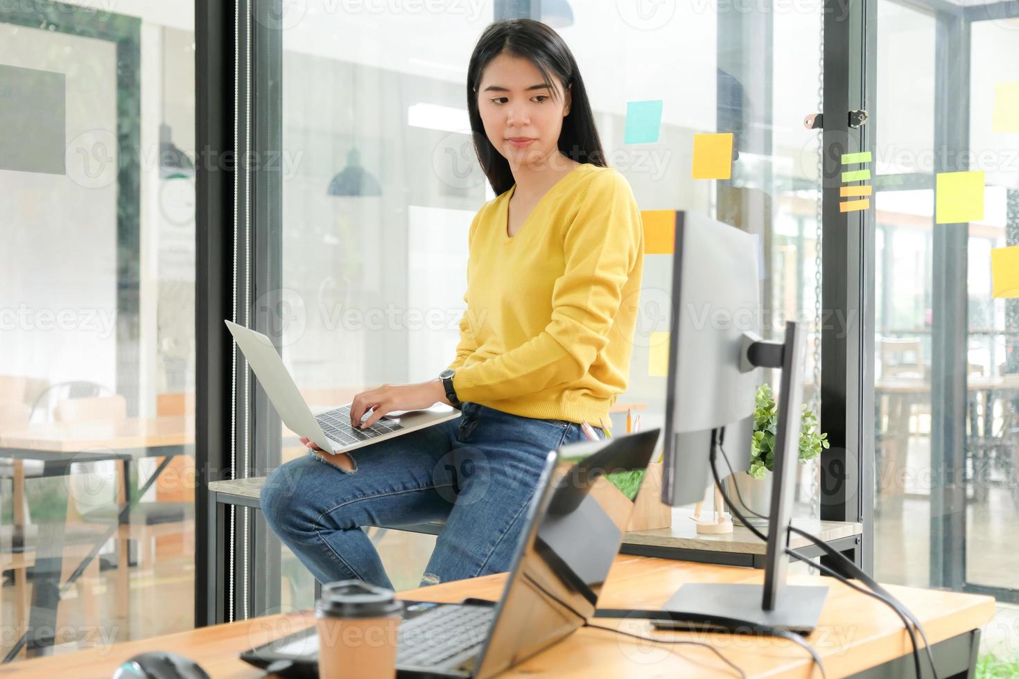 programador feminino está usando laptop para colocar na perna e criar programas para clientes. foto