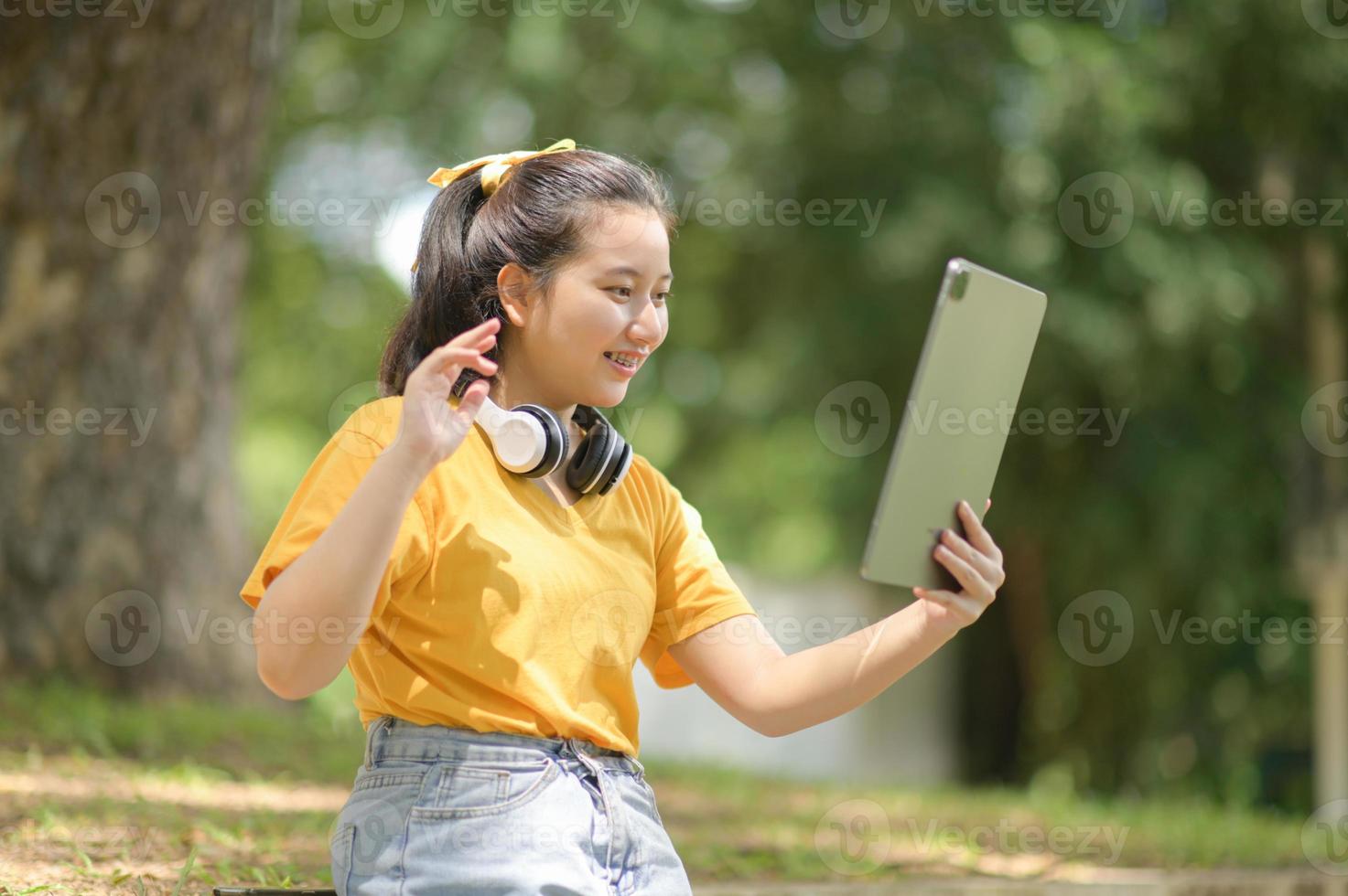 adolescente asiática cumprimenta seus amigos com um tablet. foto