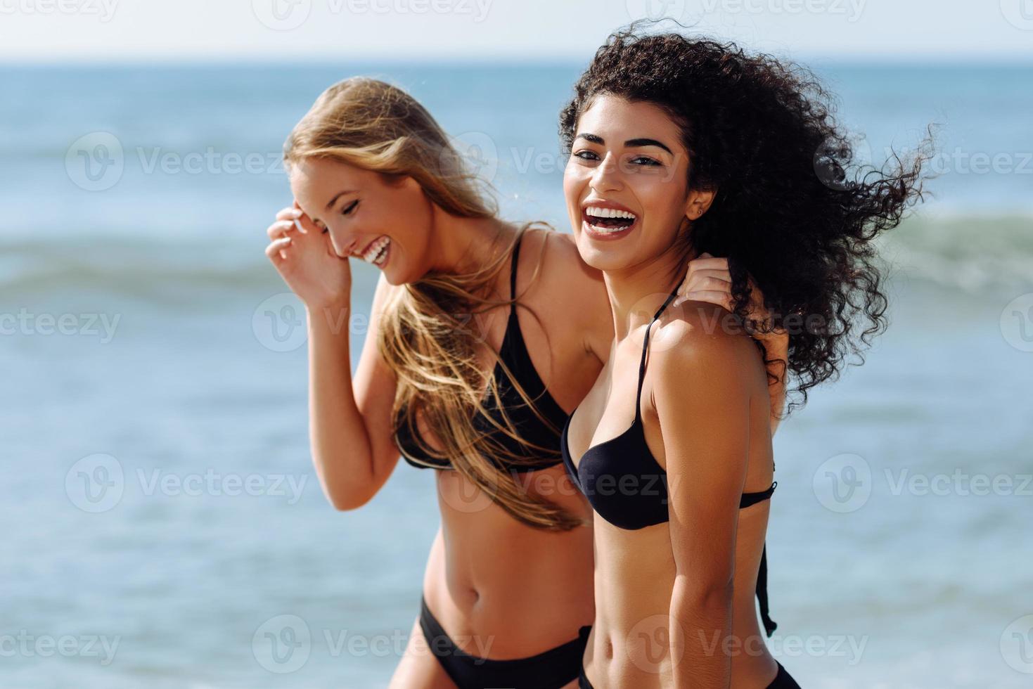 duas mulheres jovens com belos corpos em trajes de banho em uma praia tropical foto