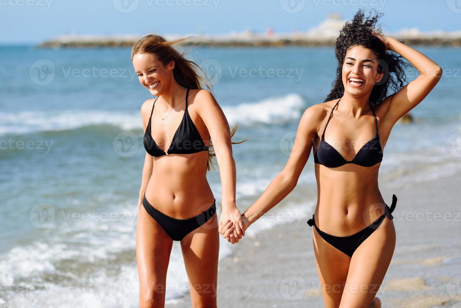 duas mulheres jovens com belos corpos em trajes de banho em uma praia tropical foto