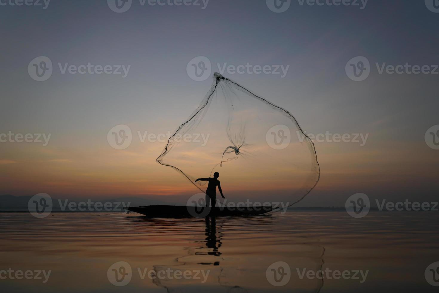 pescador jogando rede de pesca para peixe catch no lago pela manhã foto