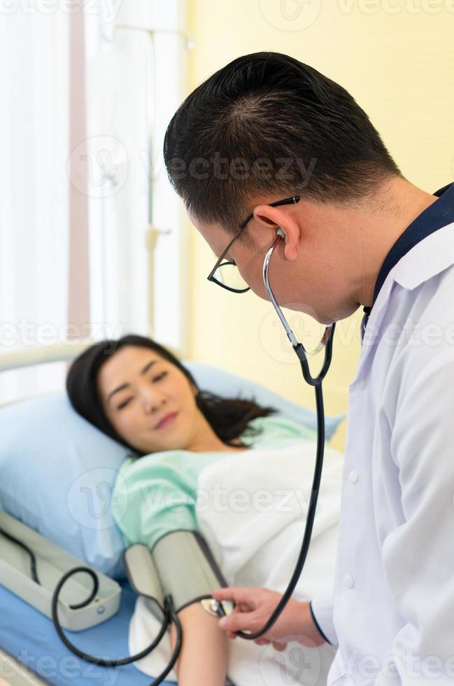 Feche a foto do médico usando o estetoscópio e o esfigmomanômetro para medir a pressão arterial do paciente no hospital. conceito de saúde e médico