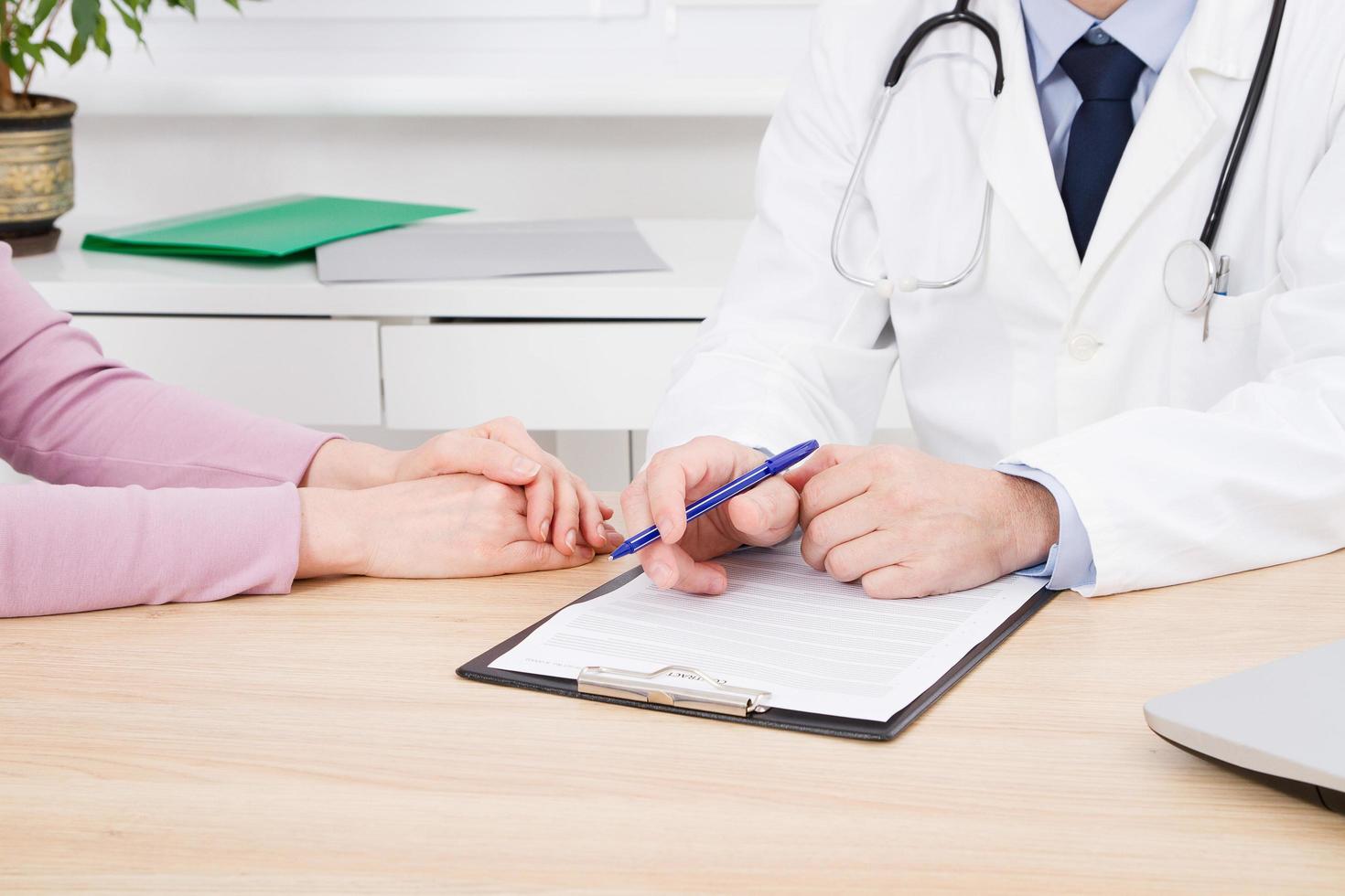 médico e paciente estão discutindo algo, apenas mãos à mesa, seguro médico. foto