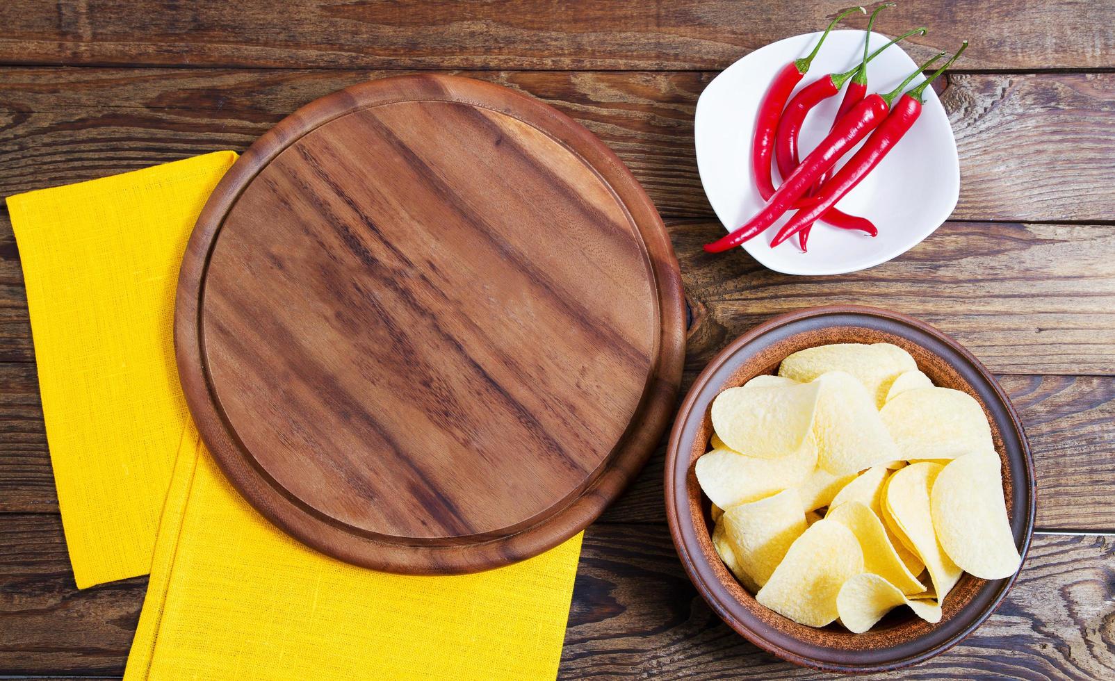 batata frita com pimenta vermelha picante e tabuleiro vazio em uma mesa de madeira foto