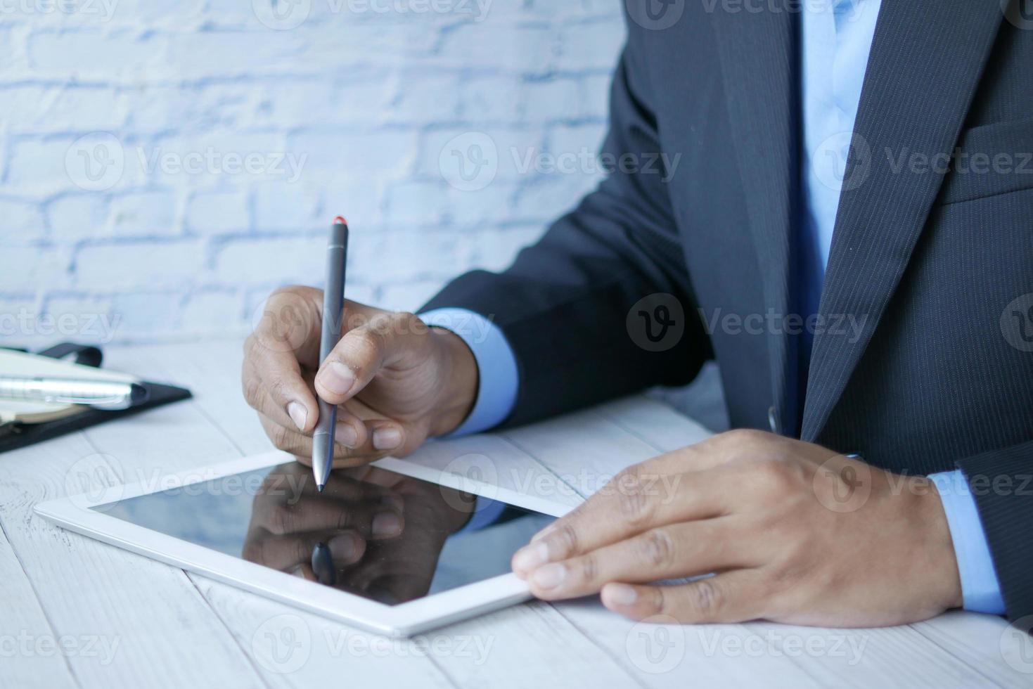 a mão do homem trabalhando em um tablet digital na mesa do escritório foto