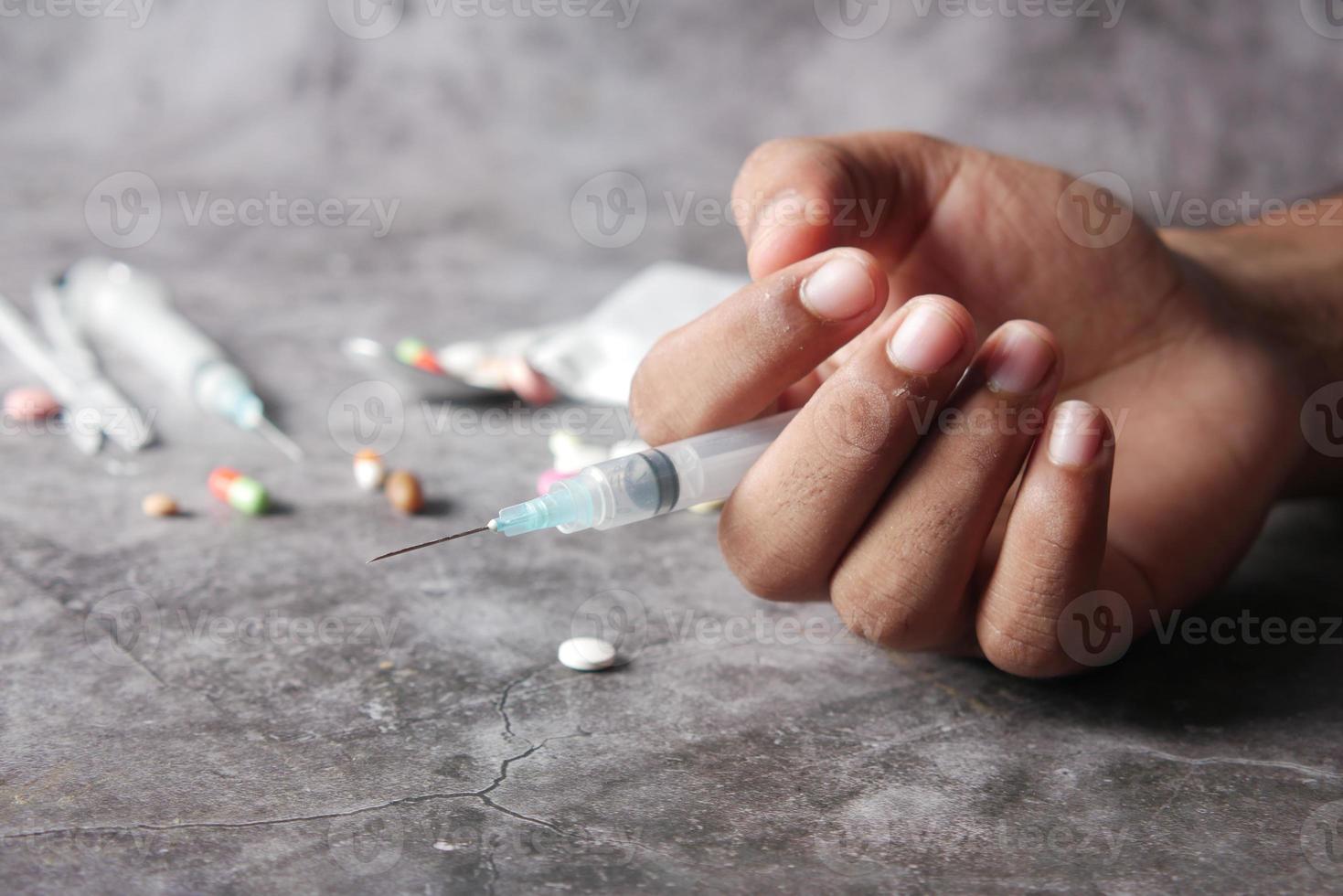 conceito de dependência de drogas segurando uma seringa e um pacote de heroína na mesa foto