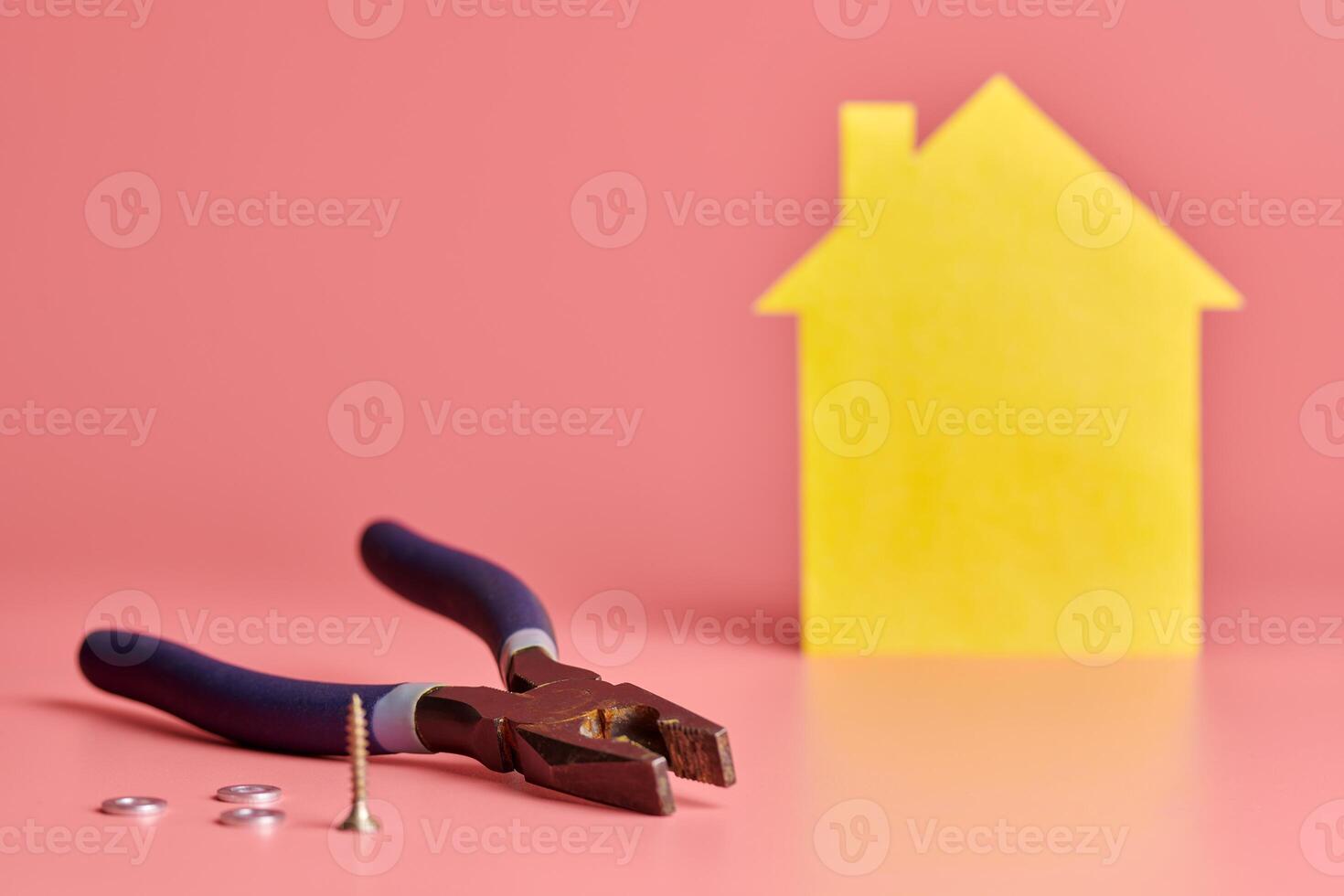 casa renovação conceito. atacante alicate, parafusos e amarelo casa em forma figura em Rosa fundo. casa reparar e redecorado. foto