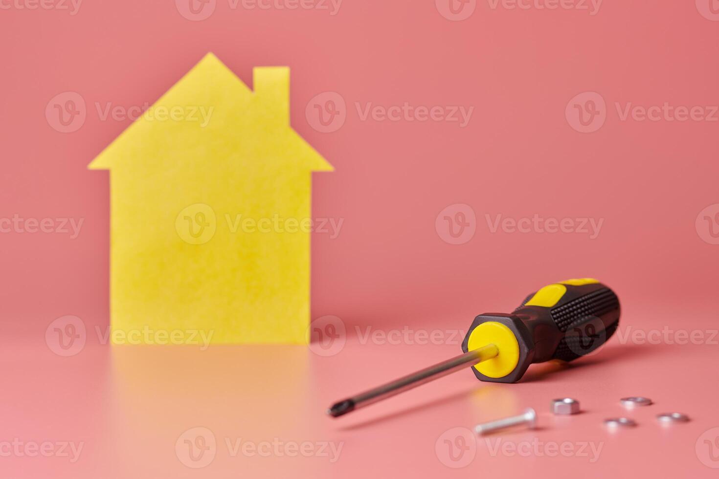 conceito de renovação de casa. reparo doméstico e redecorado. parafusos e figura em forma de casa amarela no fundo rosa. foto