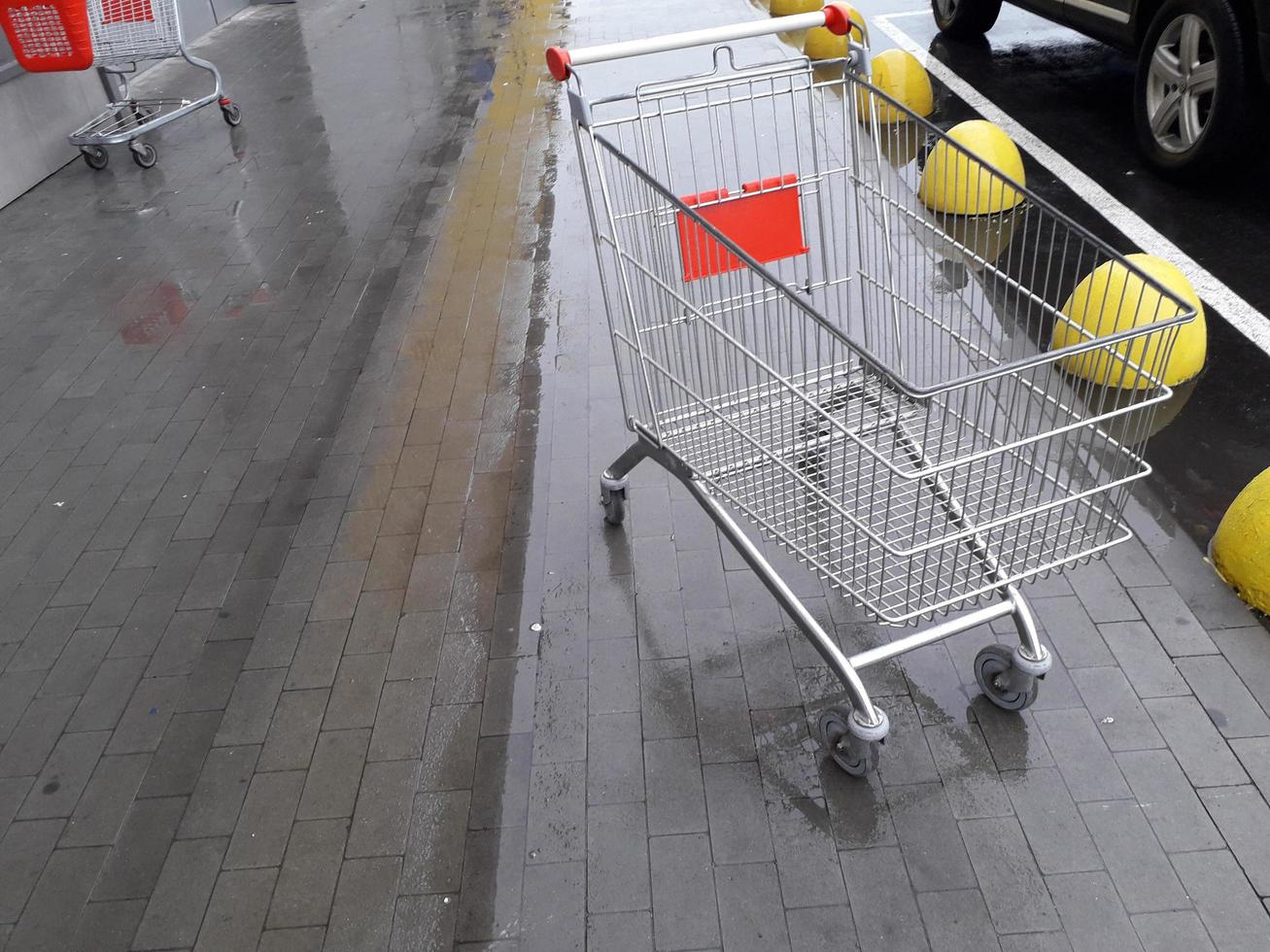 carrinhos para produtos de mercearia ficam perto de um supermercado na rua foto