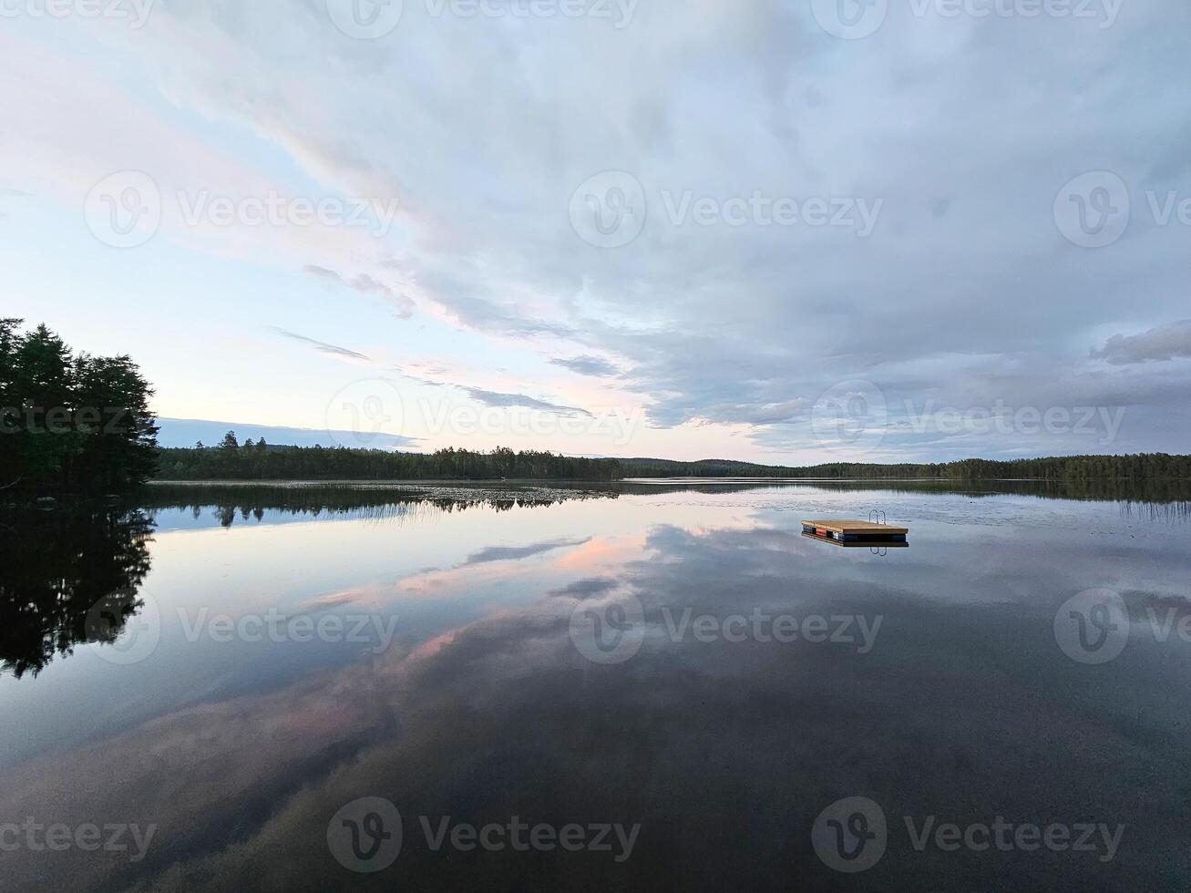 natação ilha dentro Suécia em uma lago às pôr do sol. nuvens refletido dentro a água. foto