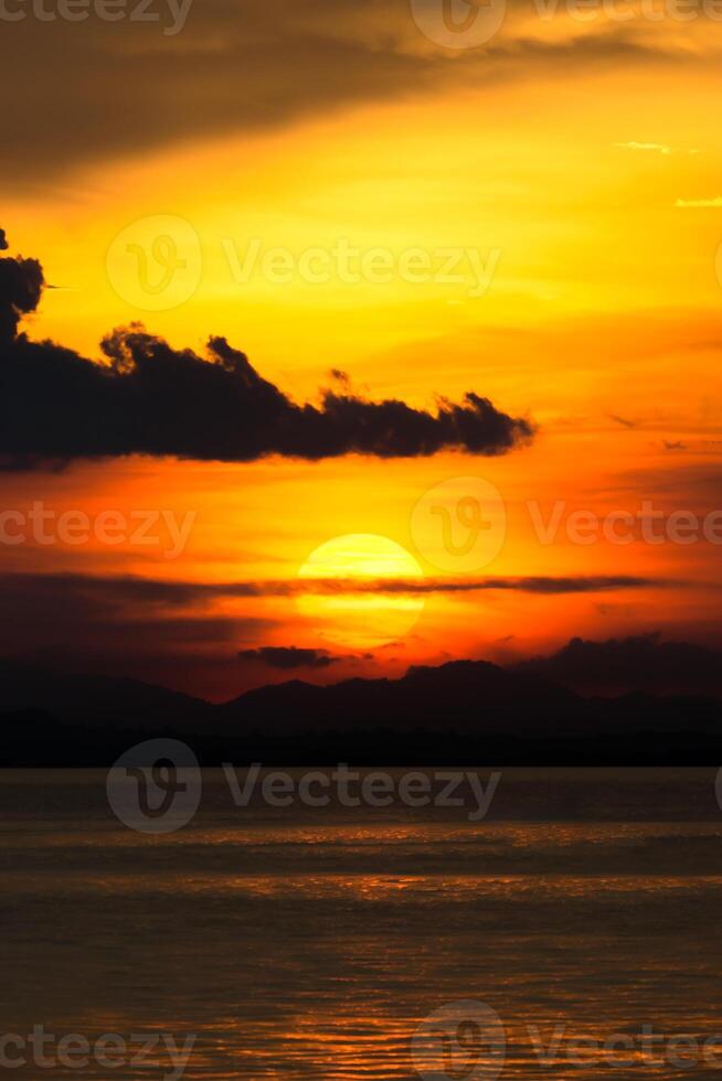 pôr do sol às a lago com Sombrio nuvem. foto