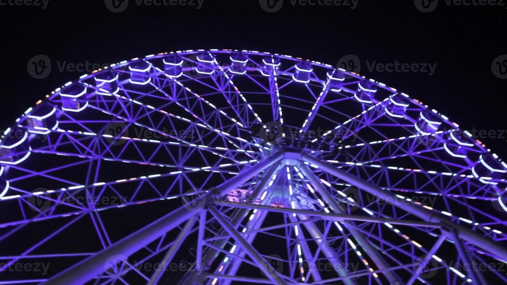 ferris roda dentro azul néon luz em Sombrio fundo, parte do ferris roda com azul iluminação contra uma Preto céu fundo às noite. ferris roda de noite. ferris roda com multicolorido foto