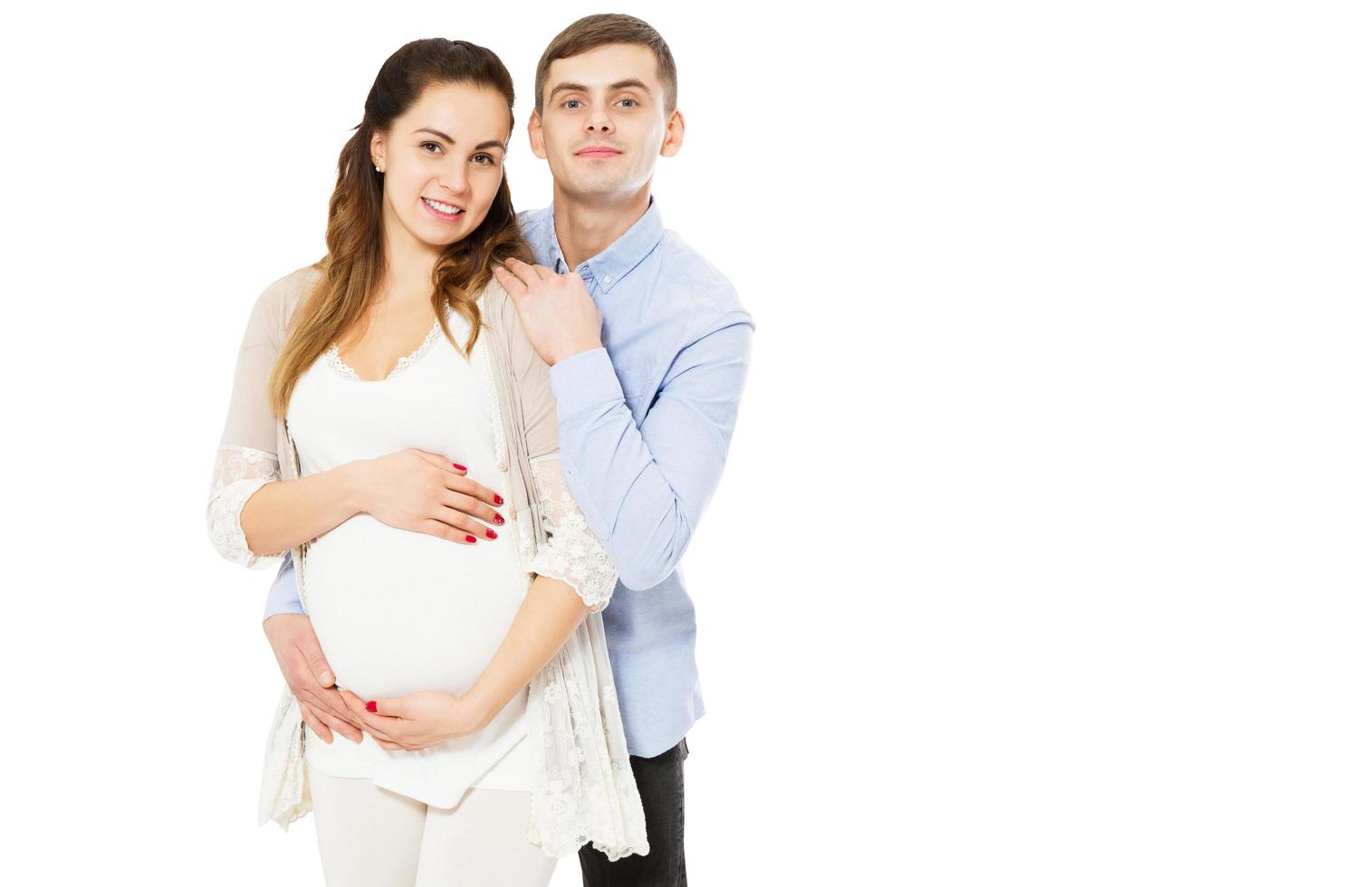 casal amoroso feliz esperando o nascimento de uma criança, posando em um fundo branco foto