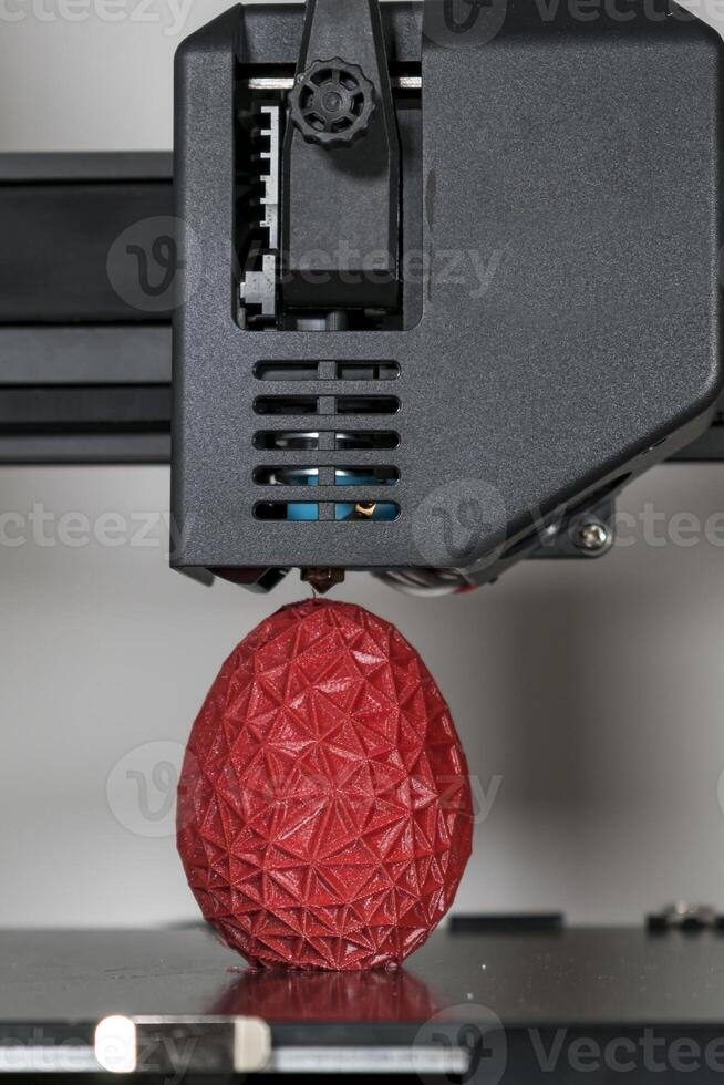 fechar acima do uma 3d impressora impressão uma vermelho poligonal ovo foto