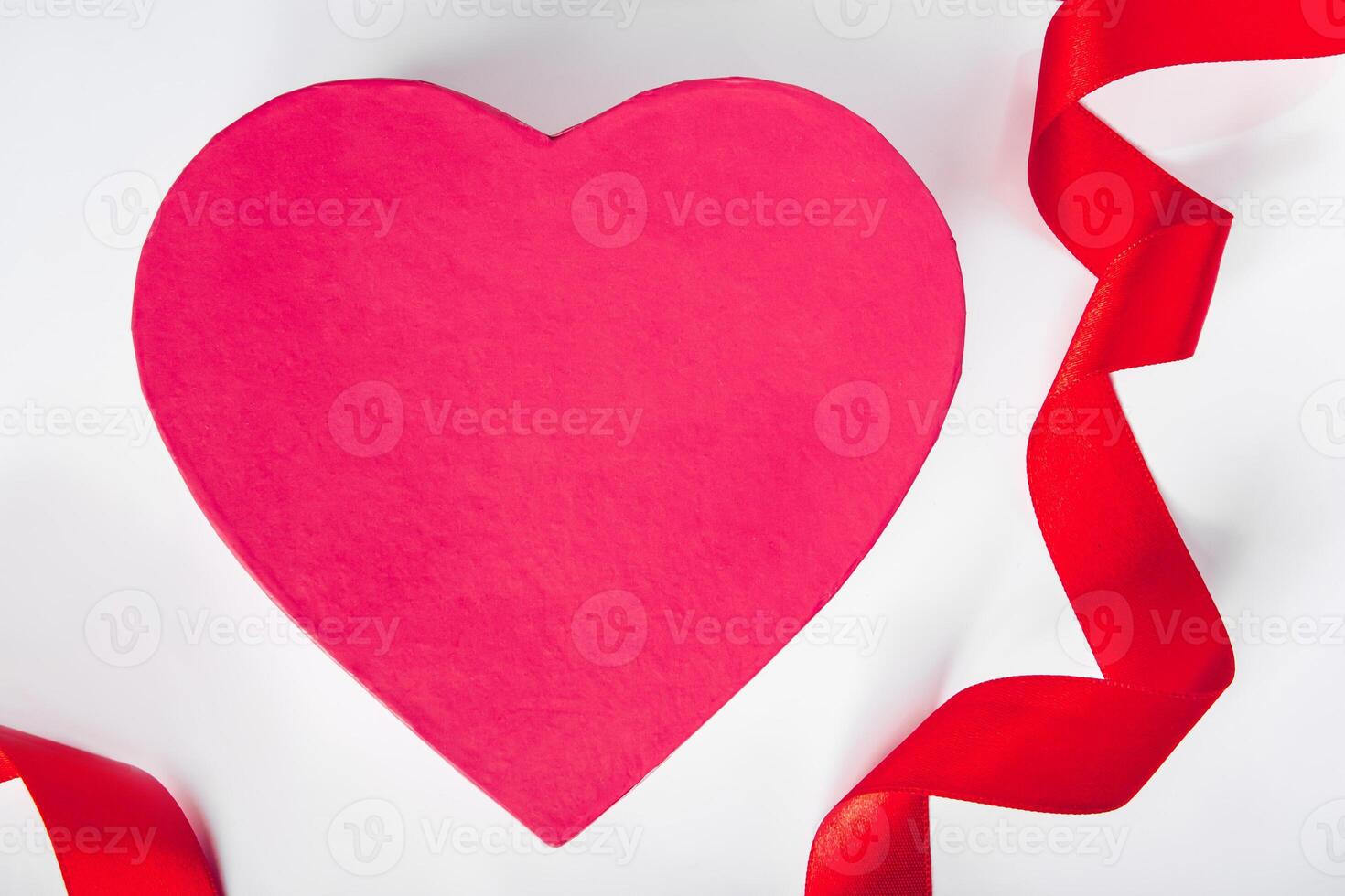 conceito de dia dos namorados. fita de seda vermelha e coração em um fundo branco. foto