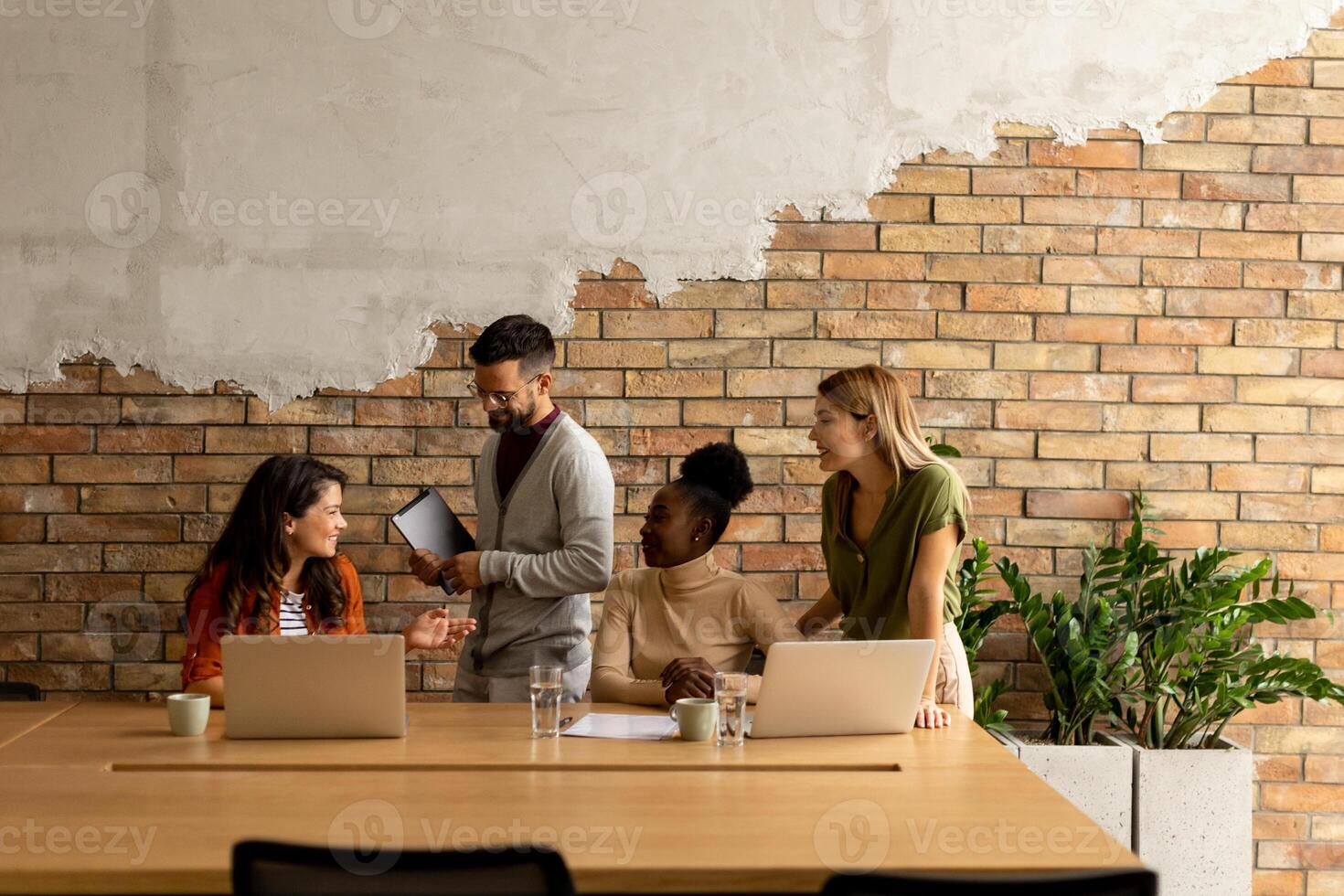 jovem multiétnico comece equipe trabalhando de a tijolo parede dentro a industrial estilo escritório foto