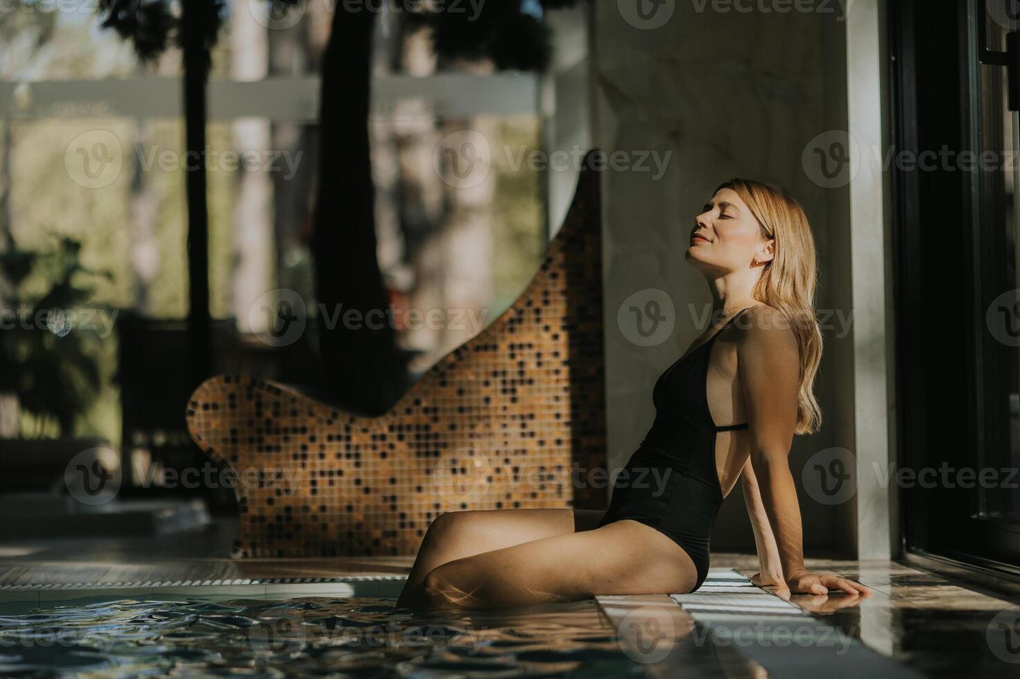 jovem mulher relaxante de a interior natação piscina foto