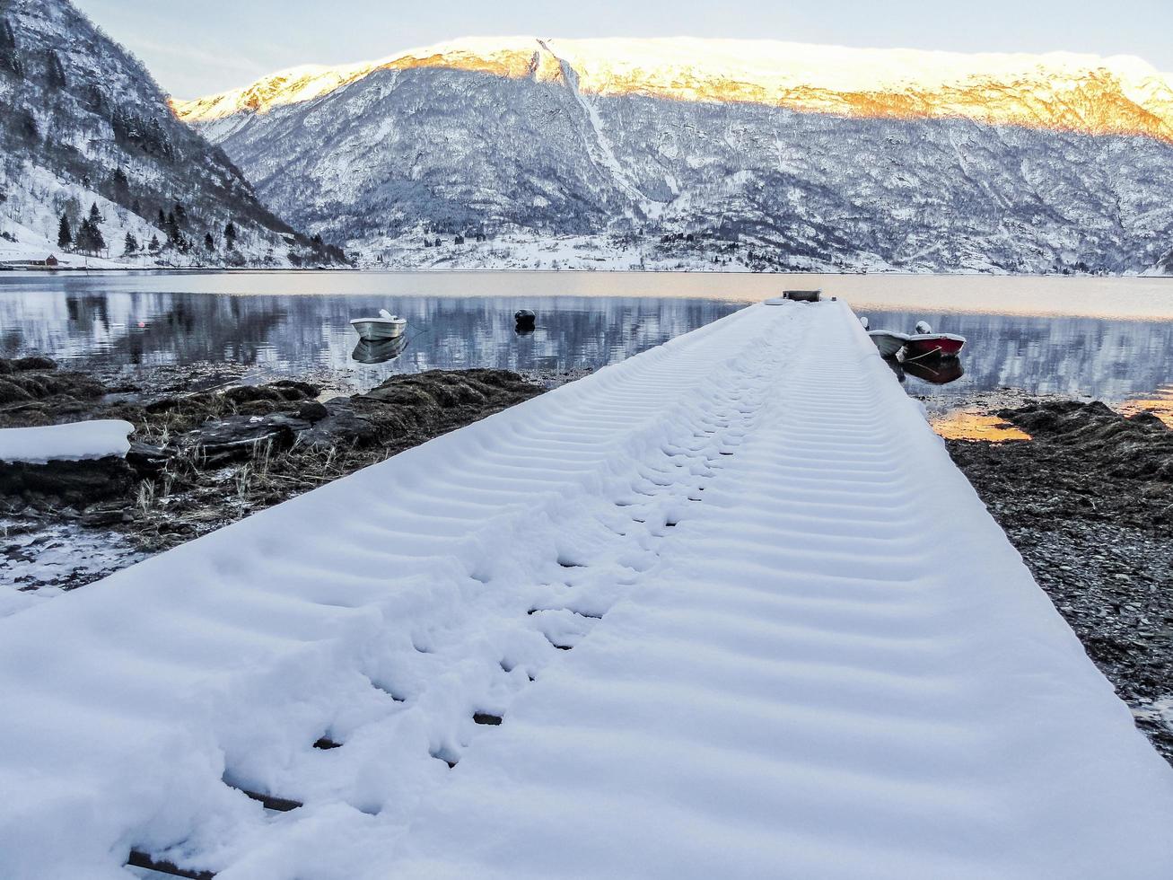 paisagem de inverno do cais coberto de neve no lago fiorde na Noruega. foto