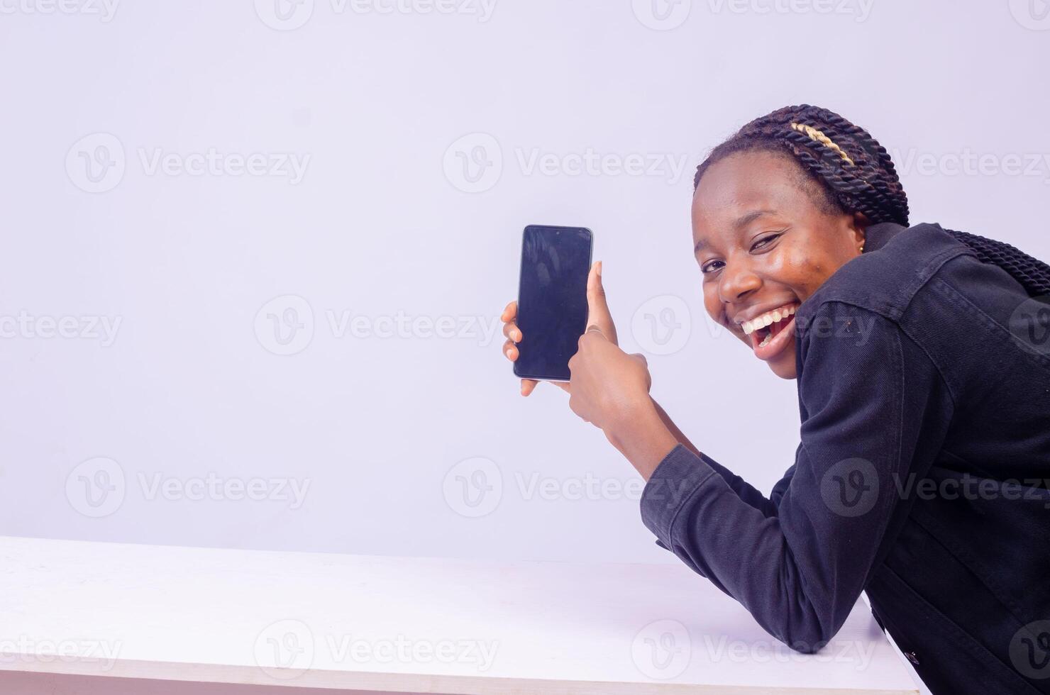 retrato do uma lindo jovem Preto mulher sorridente enquanto mostrando dela telefone tela foto