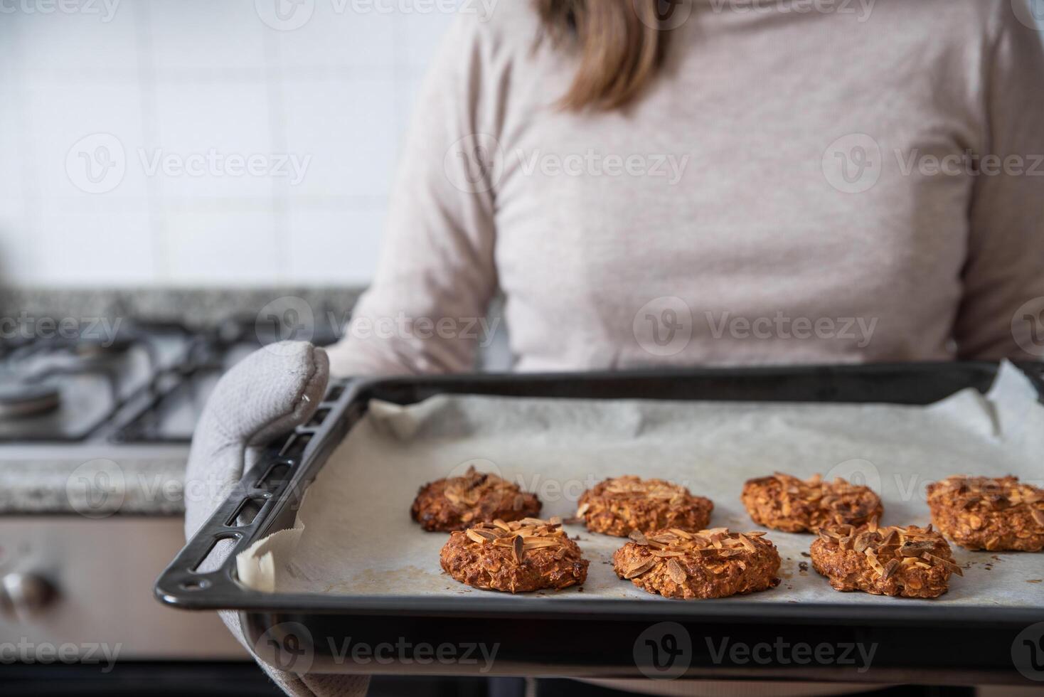 mulher segurando cozimento bandeja com pronto biscoitos. foto