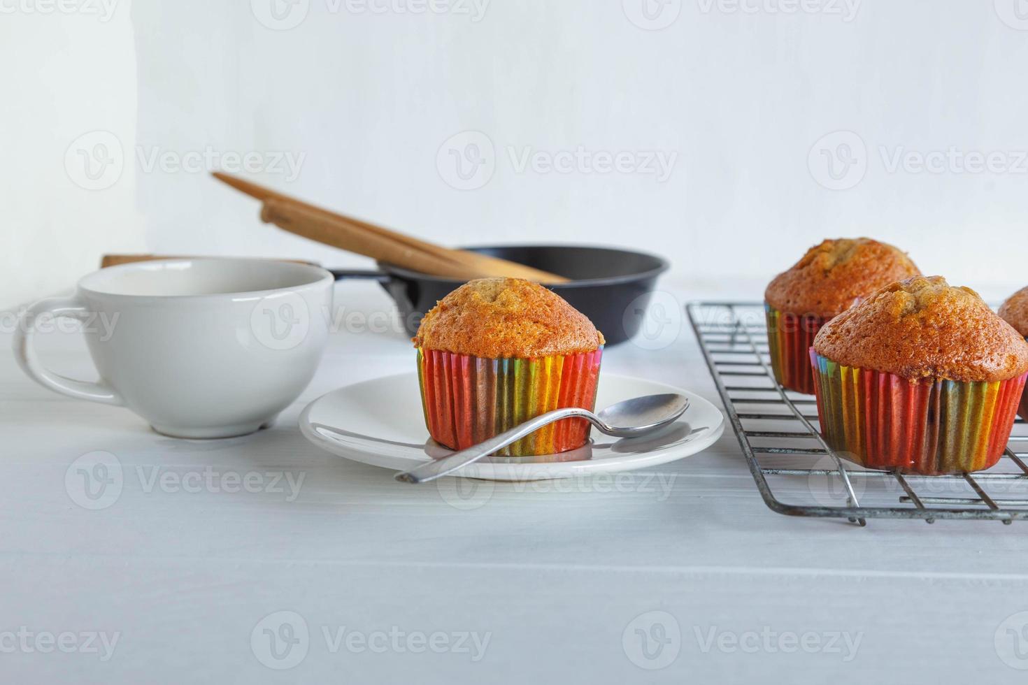 cupcakes caseiros e xícara de café na mesa branca foto