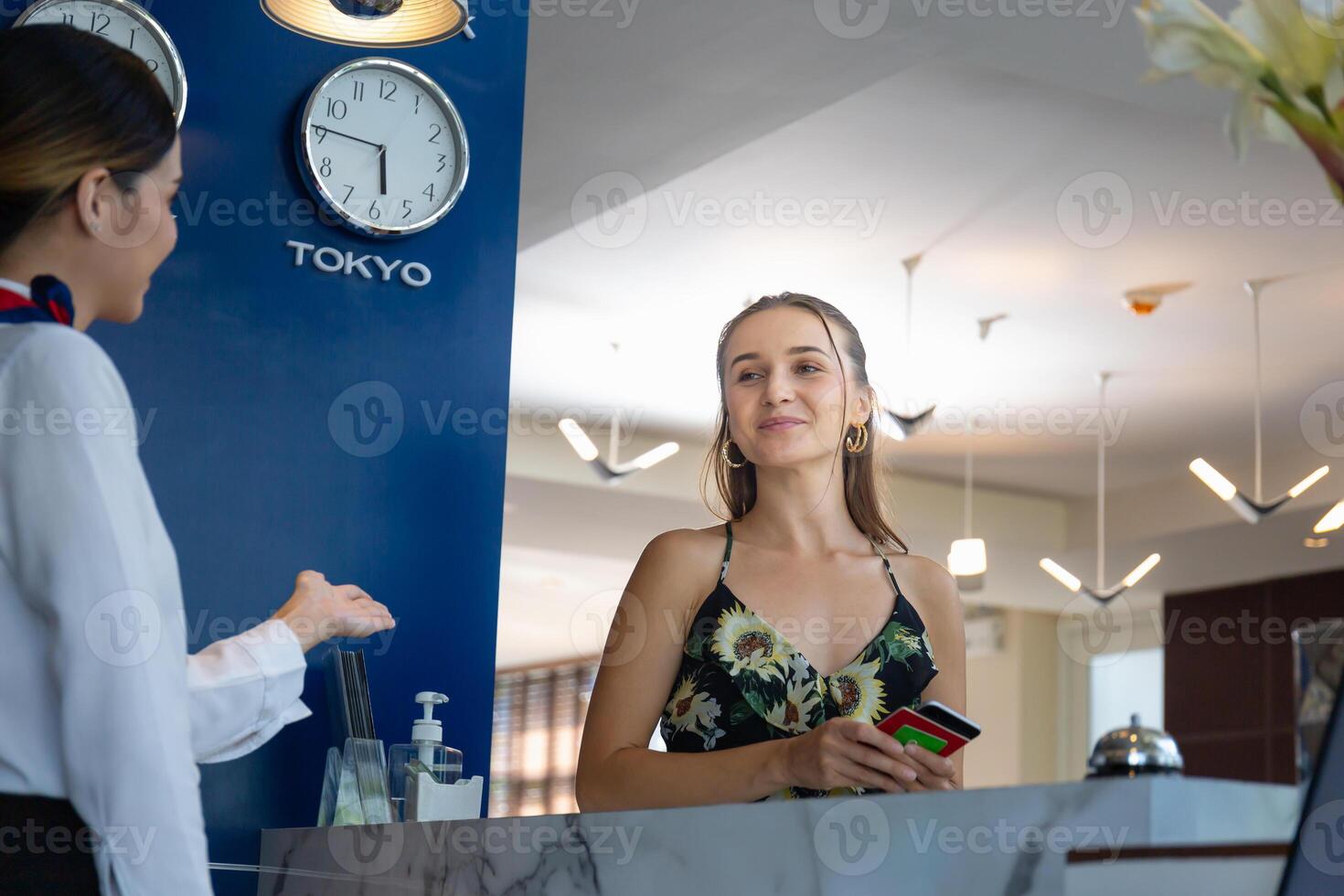 fêmea Viajantes check-in às a hotel com borrado sorridente fêmea recepcionista foto